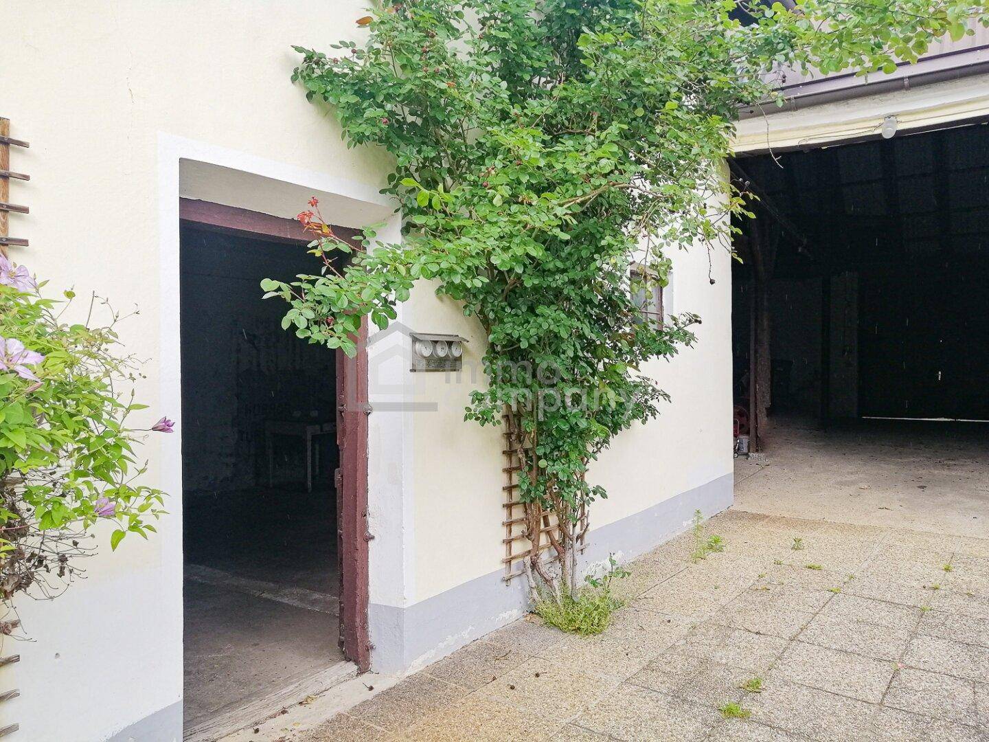 Hofbereich mit gepflastertem Boden und offenem Zugang zu einer Scheune oder Garage.