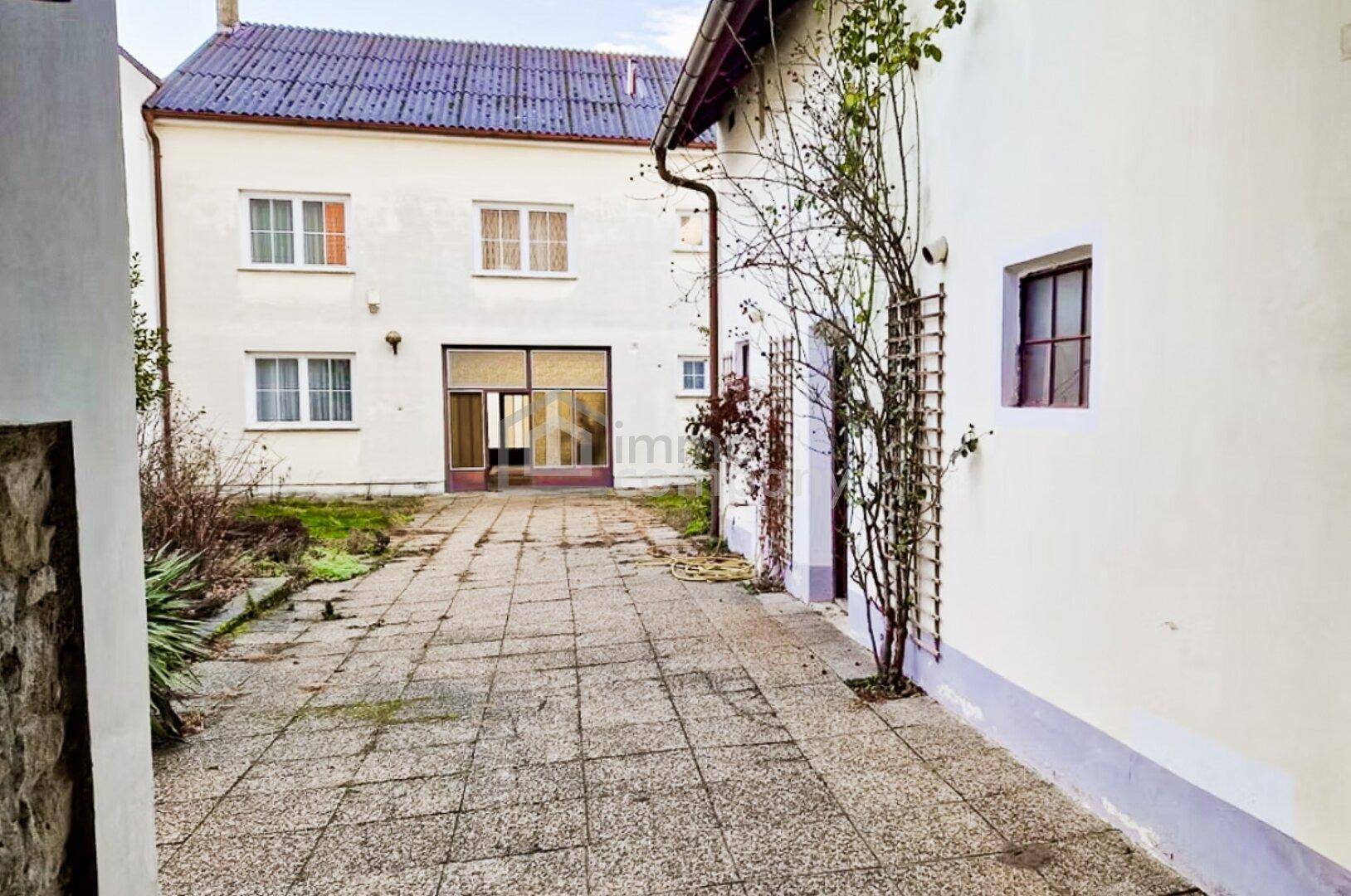 Hinterhof mit gepflastertem Bereich zwischen zwei Gebäuden und Blick auf eine weitere Fassade.