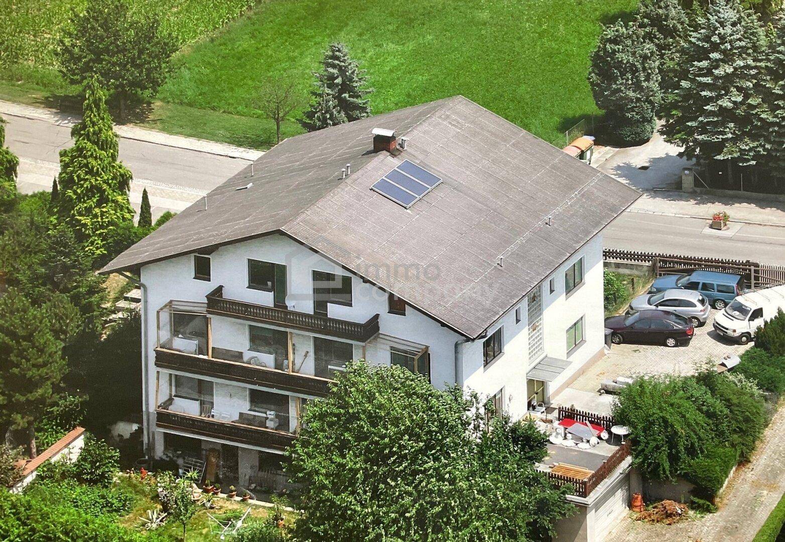 Luftaufnahme des Gebäudes mit Solaranlage auf dem Dach und umliegender Grünfläche.