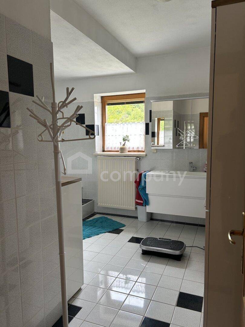 Helles Badezimmer mit schwarz-weißen Fliesen, Fenster und modernem Waschtisch.