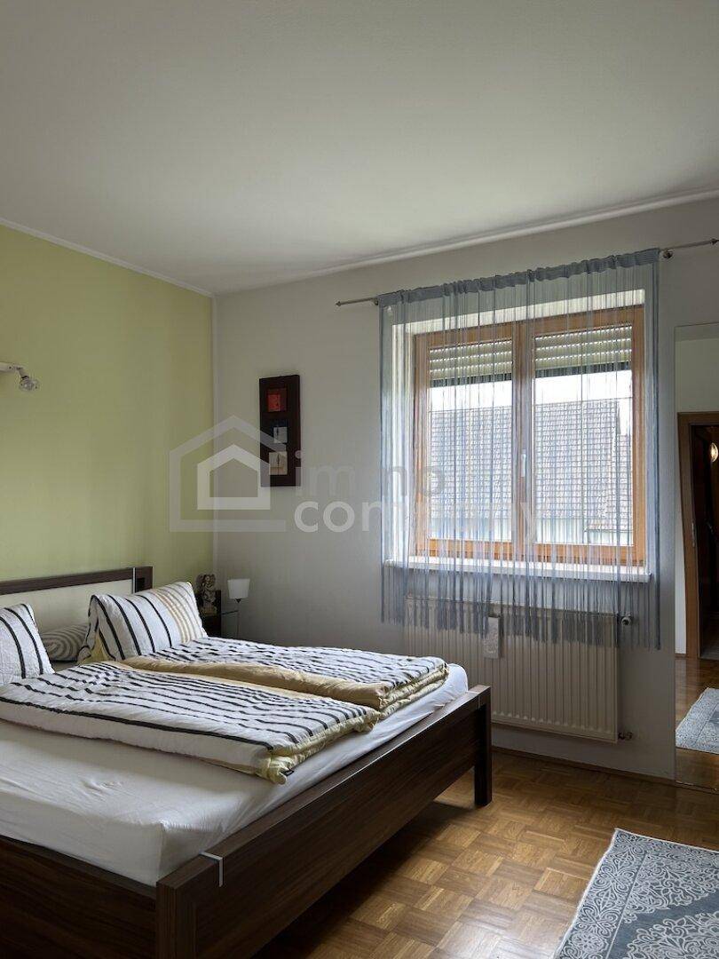 Schlafzimmer mit Doppelbett, Parkettboden und Fenster mit Rollladen, hell und freundlich.