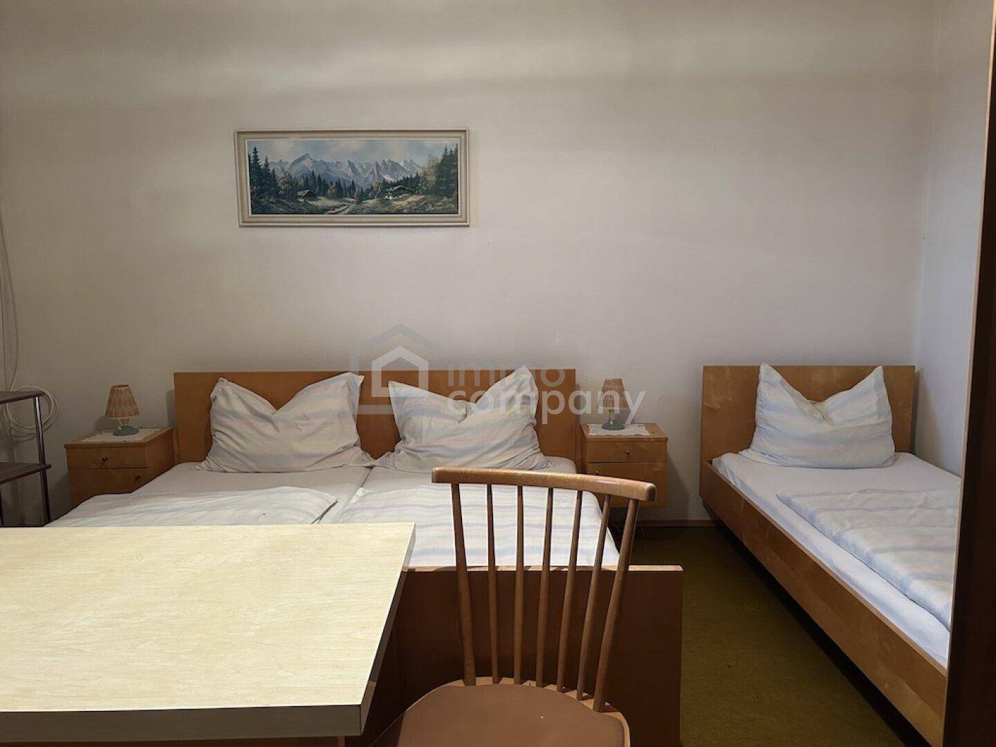 Einfaches Schlafzimmer mit zwei Einzelbetten und einem zusätzlichen Bett, ideal für Gäste.