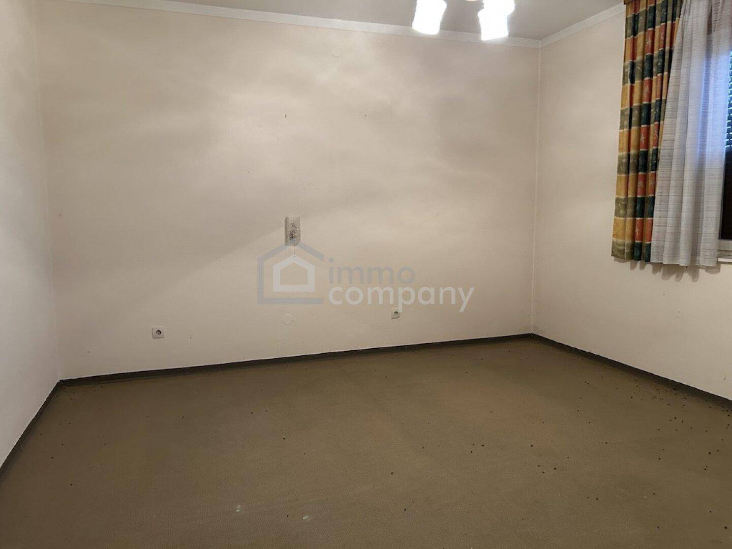 Leeres Schlafzimmer mit Teppichboden und Fenster, bereit zur individuellen Gestaltung.
