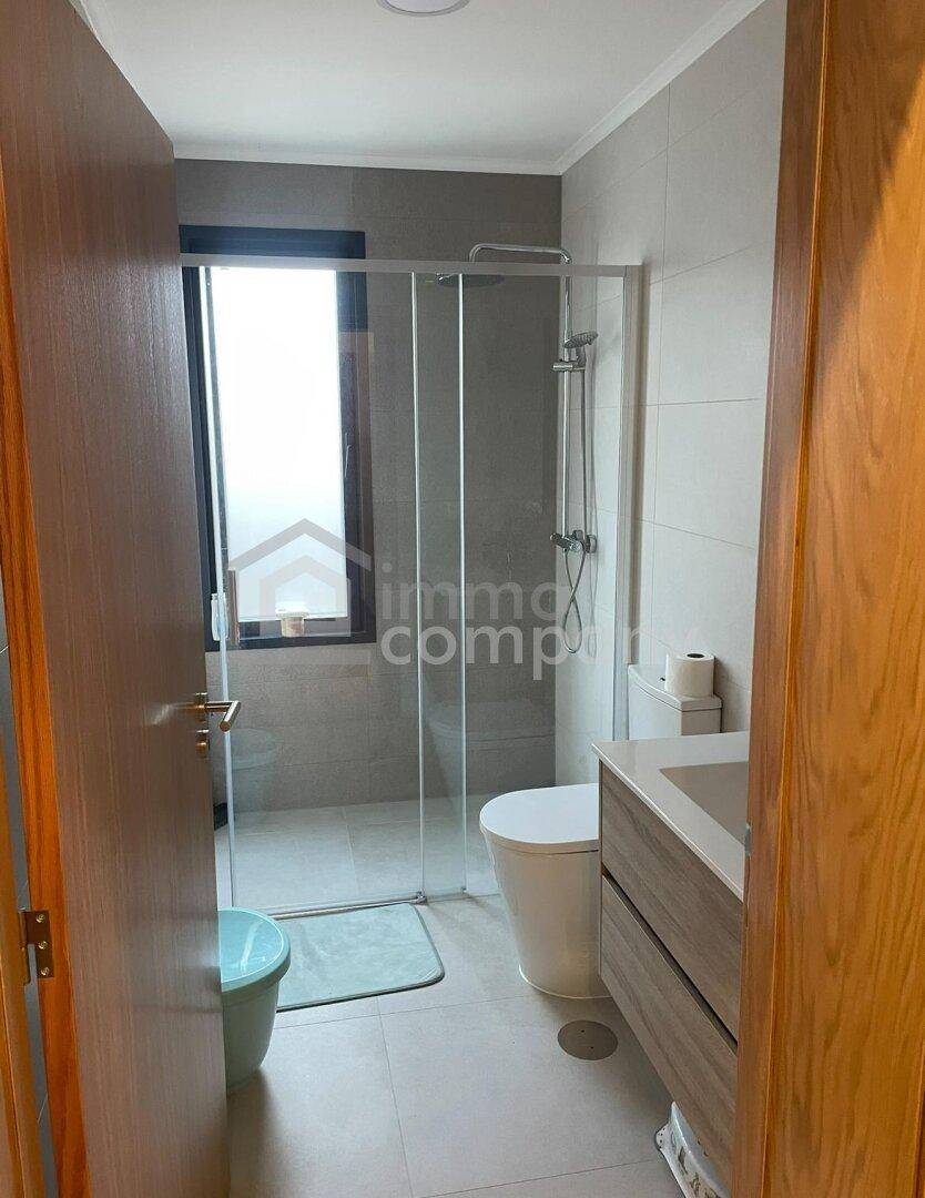 Modernes Badezimmer mit begehbarer Dusche, WC und Waschtischunterschrank in neutralen Farben.
