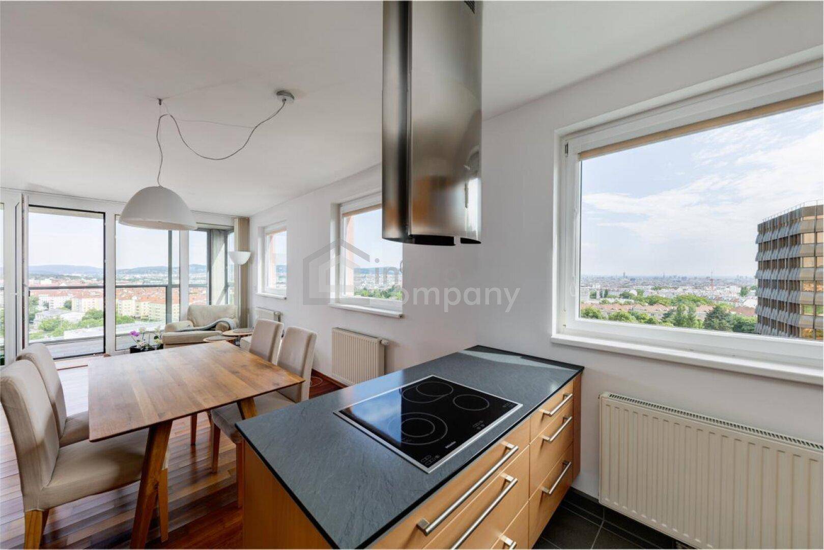 Offene Küche mit Kochinsel, Induktionskochfeld und Essbereich mit Stadtblick.