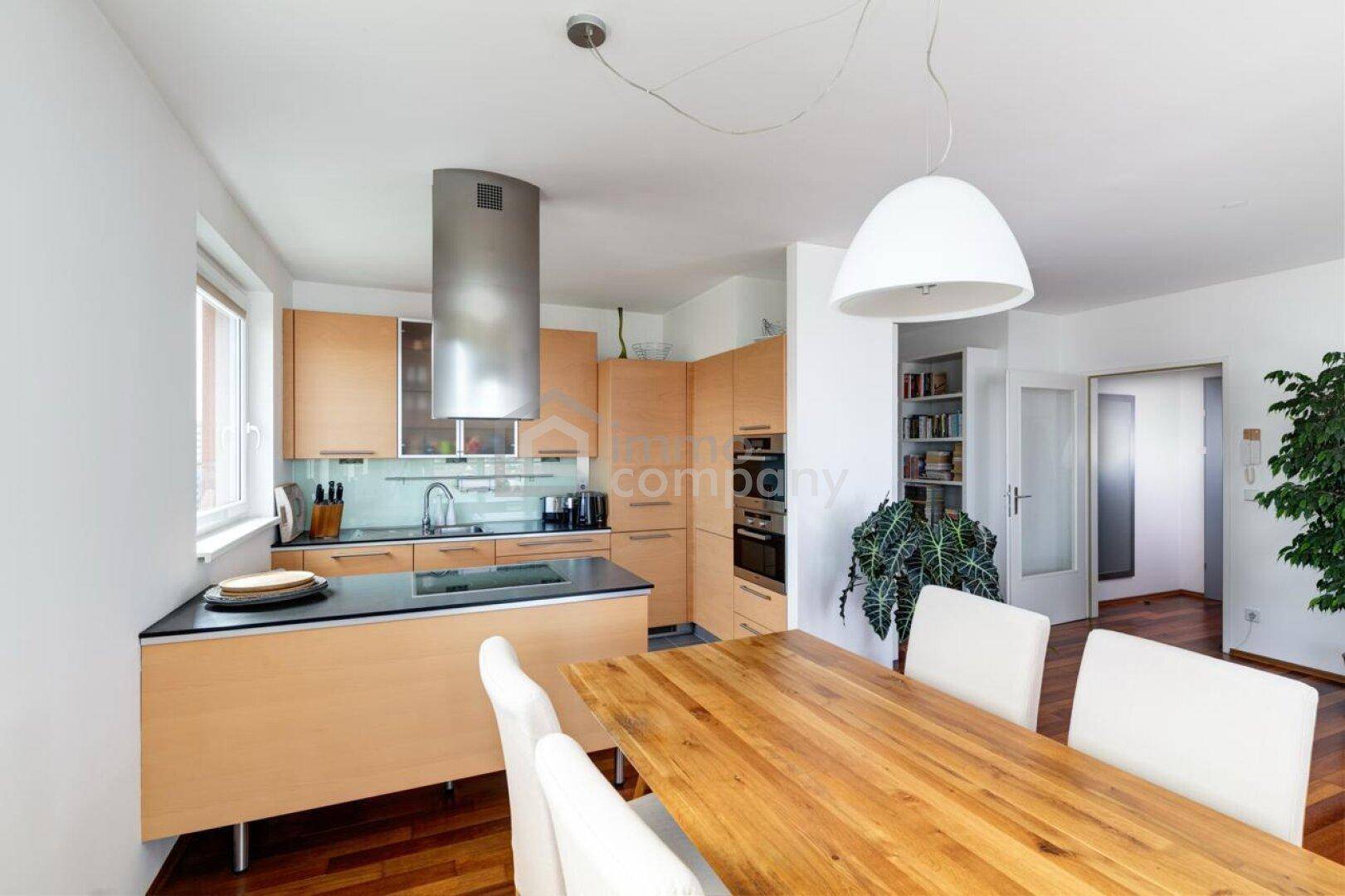 Moderne Einbauküche mit Holzfronten, dunkler Arbeitsplatte und Essbereich.
