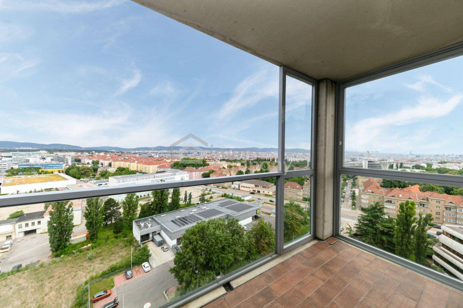 Verglaster Balkon mit weitem Stadtblick und umliegender Landschaft.