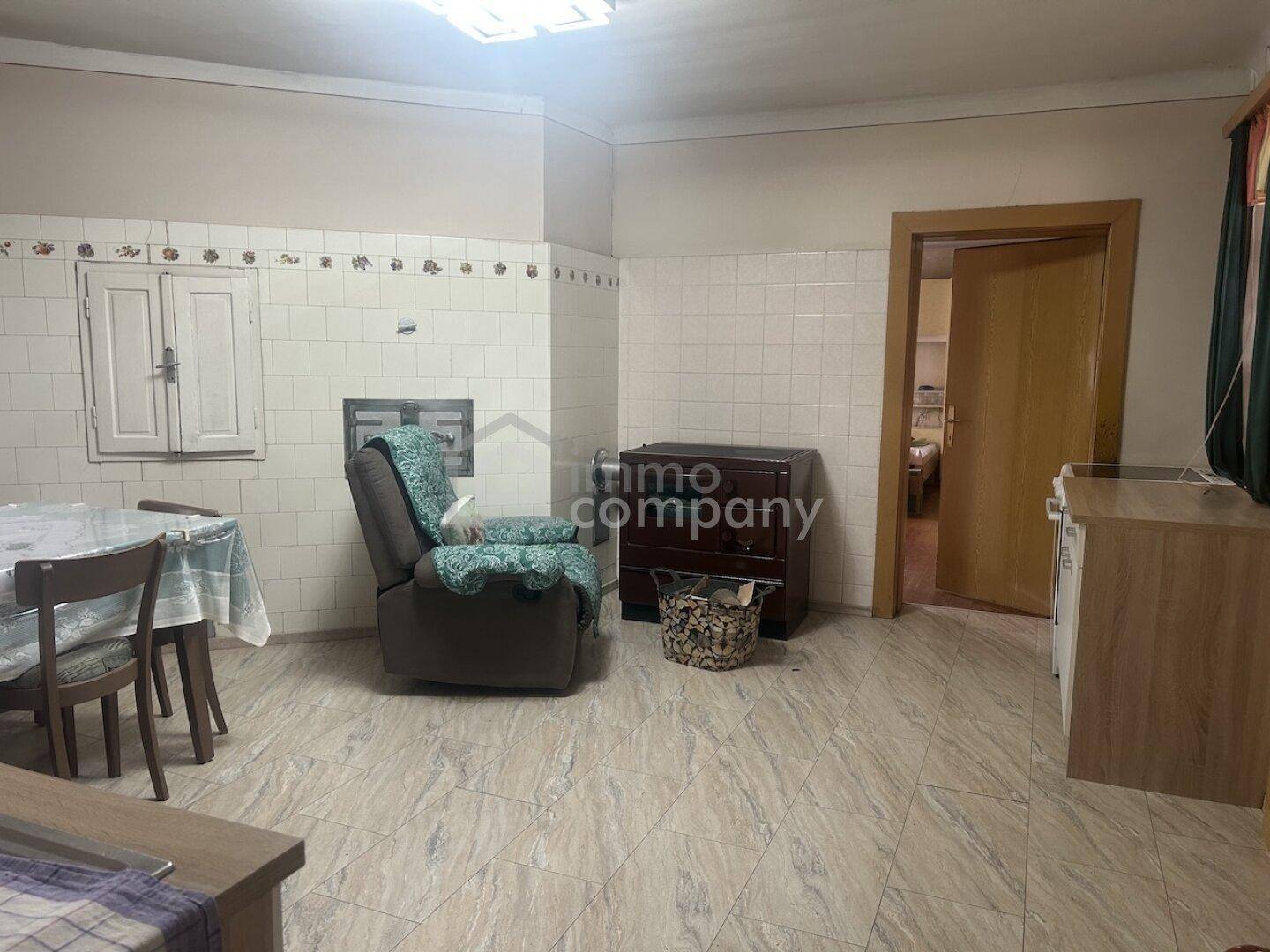 Gemütlicher Wohnbereich mit Fliesenboden, gefliesten Wänden und einem Sessel, der zum Entspannen einlädt.