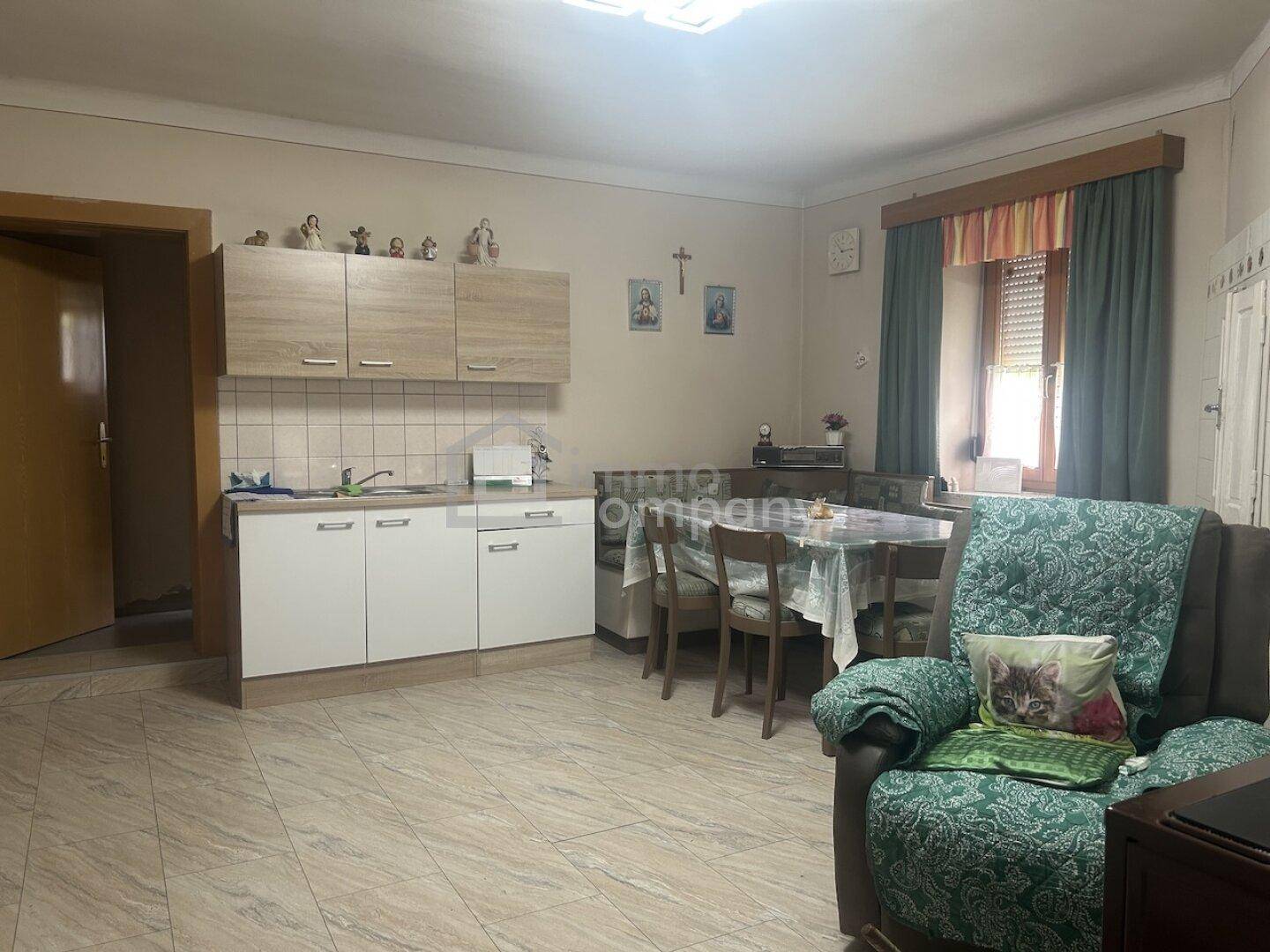 Funktionale Küche mit hellen Schränken, Spüle und Essbereich, integriert in einen offenen Raum.