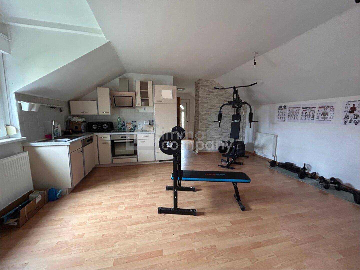Vielseitiger Raum im Dachgeschoss, eingerichtet als Fitnessbereich mit kleiner Küchenzeile.