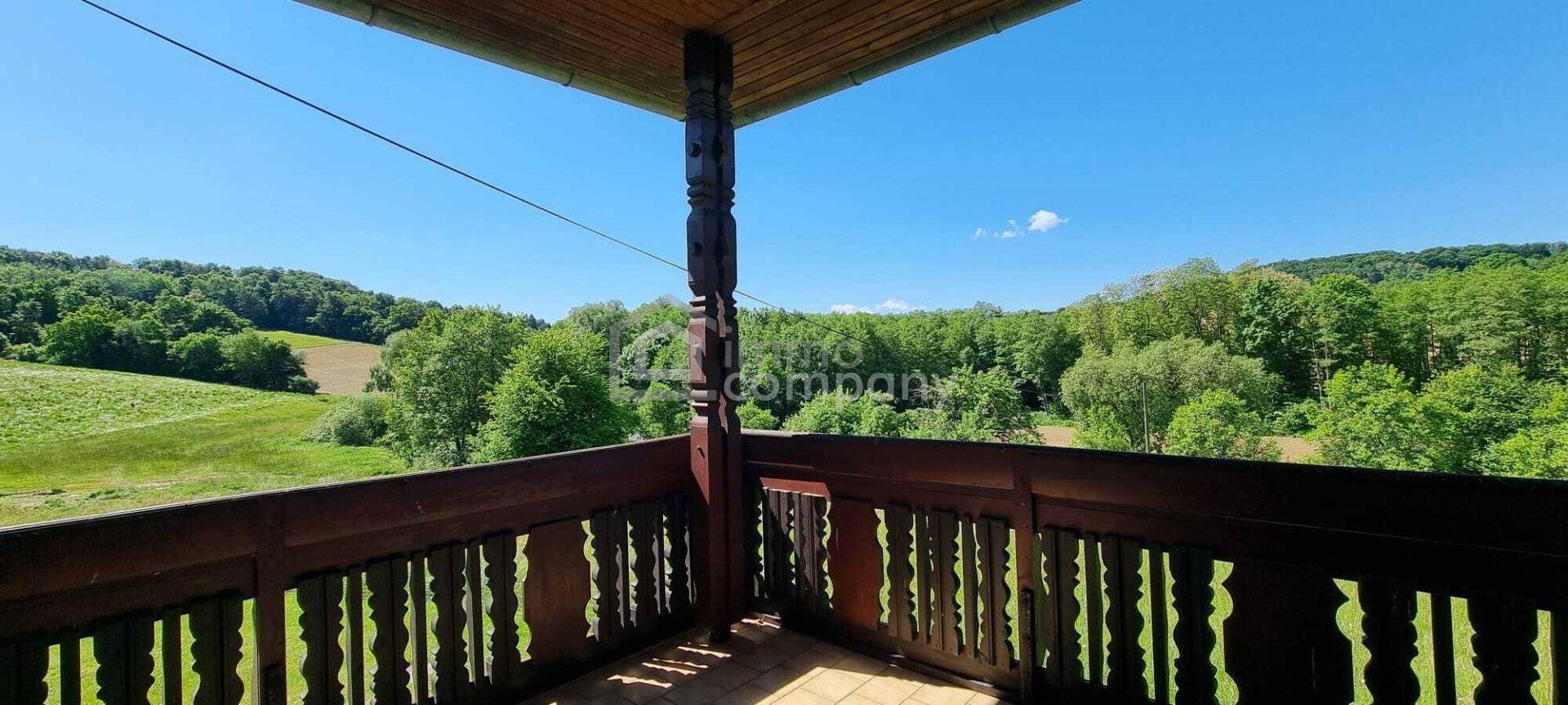 Balkon mit traditionellem Holzgeländer und weitem Blick über die grüne Landschaft.