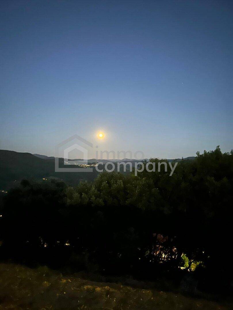 Malerischer Nachthimmel mit hellem Mond über einer dunklen, hügeligen Landschaft.