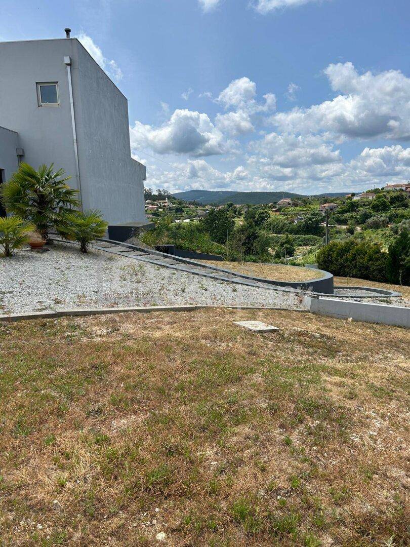 Moderne Villa mit terrassierter Landschaftsgestaltung und weitem Blick in die grüne Landschaft.
