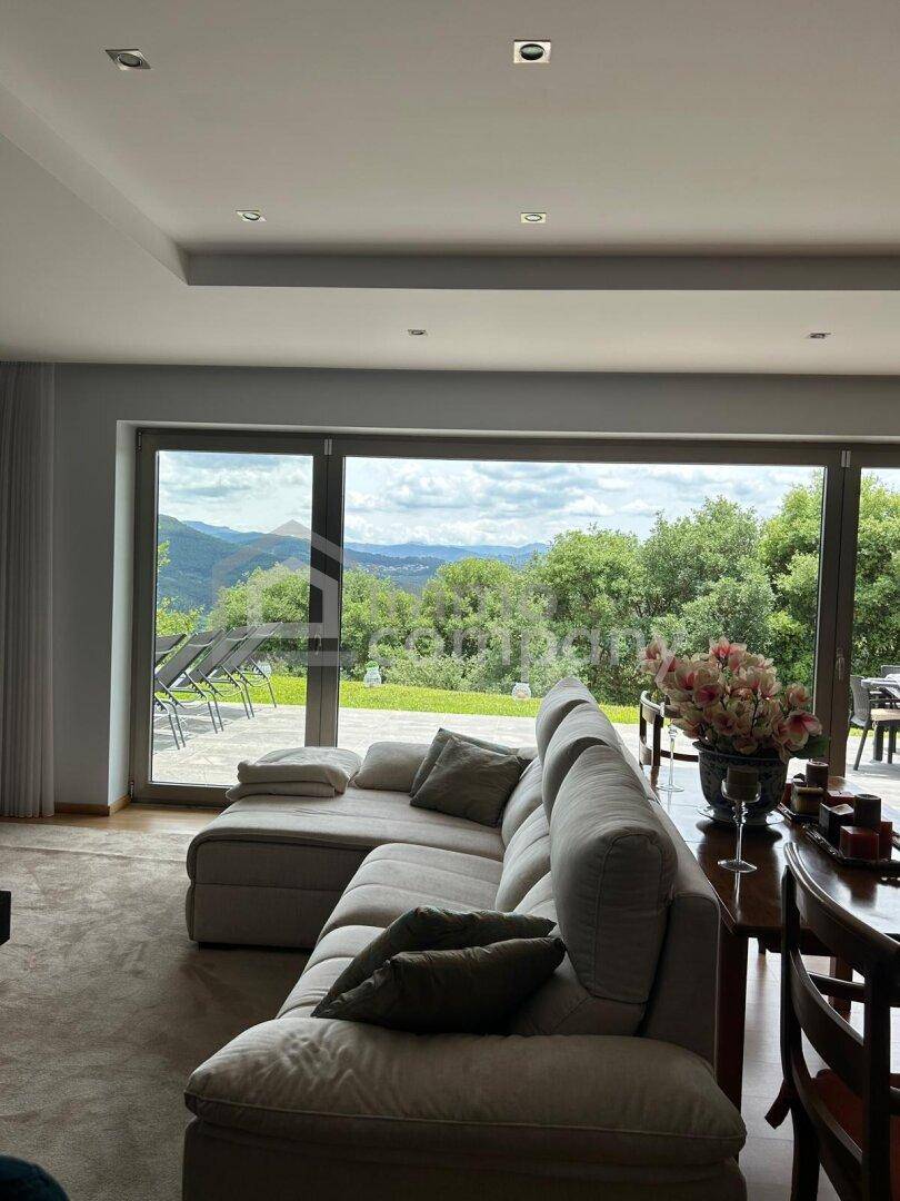 Geräumiges Wohnzimmer mit großen Fenstern, die einen atemberaubenden Blick auf die grüne Landschaft bieten.
