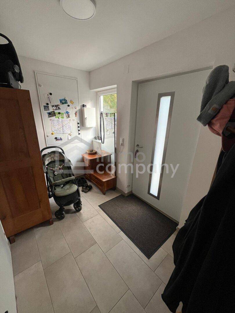 Heller Eingangsbereich mit Fliesenboden, Haustür und praktischen Ablagemöglichkeiten.