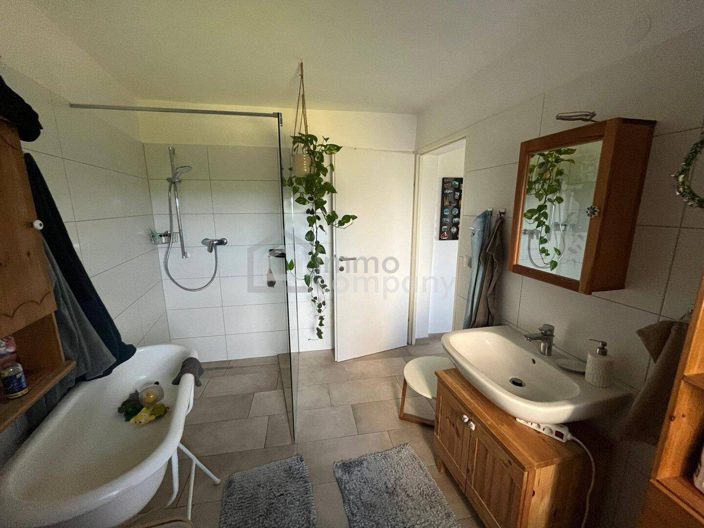 Modernes Badezimmer mit freistehender Badewanne, begehbarer Dusche und Holzwaschtisch.