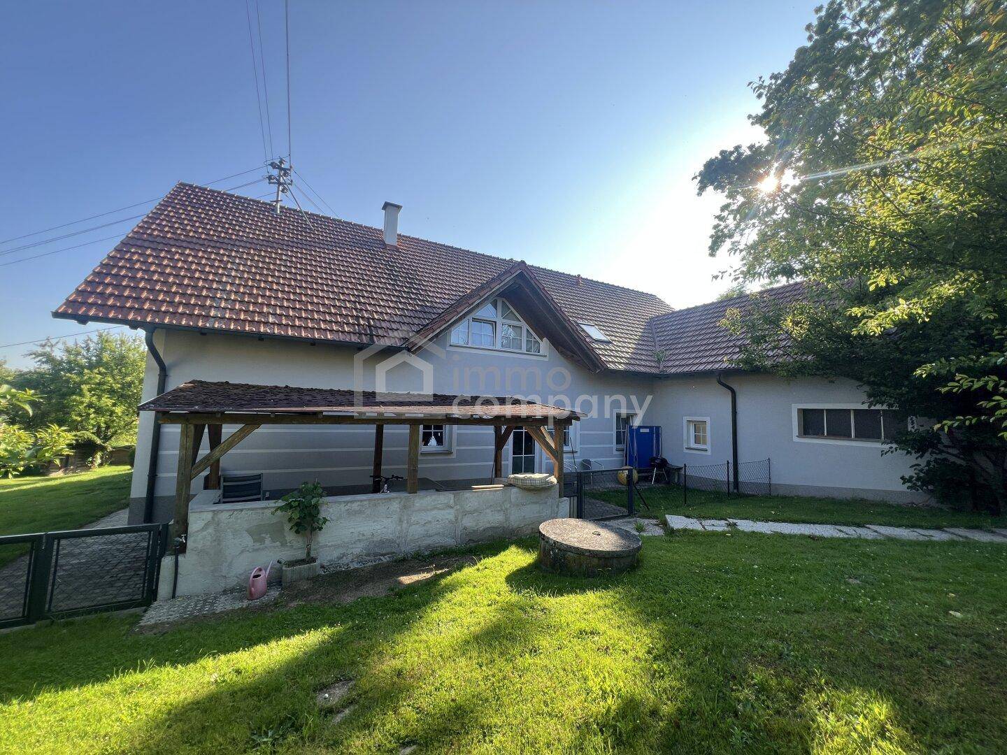 Seitenansicht des Hauses mit überdachter Terrasse und großem Gartenbereich.