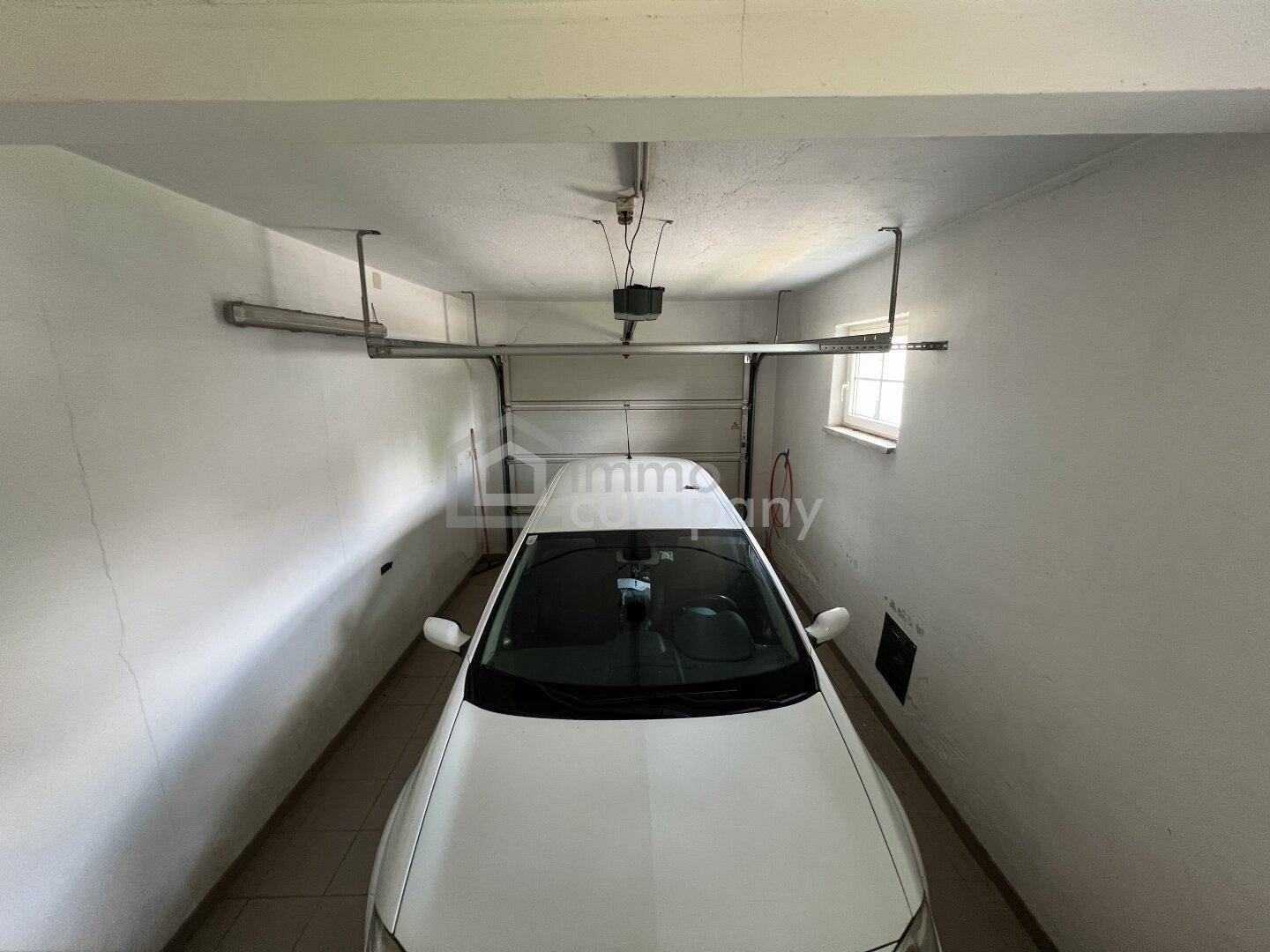 Einzelgarage mit einem geparkten Auto und ausreichend Platz.