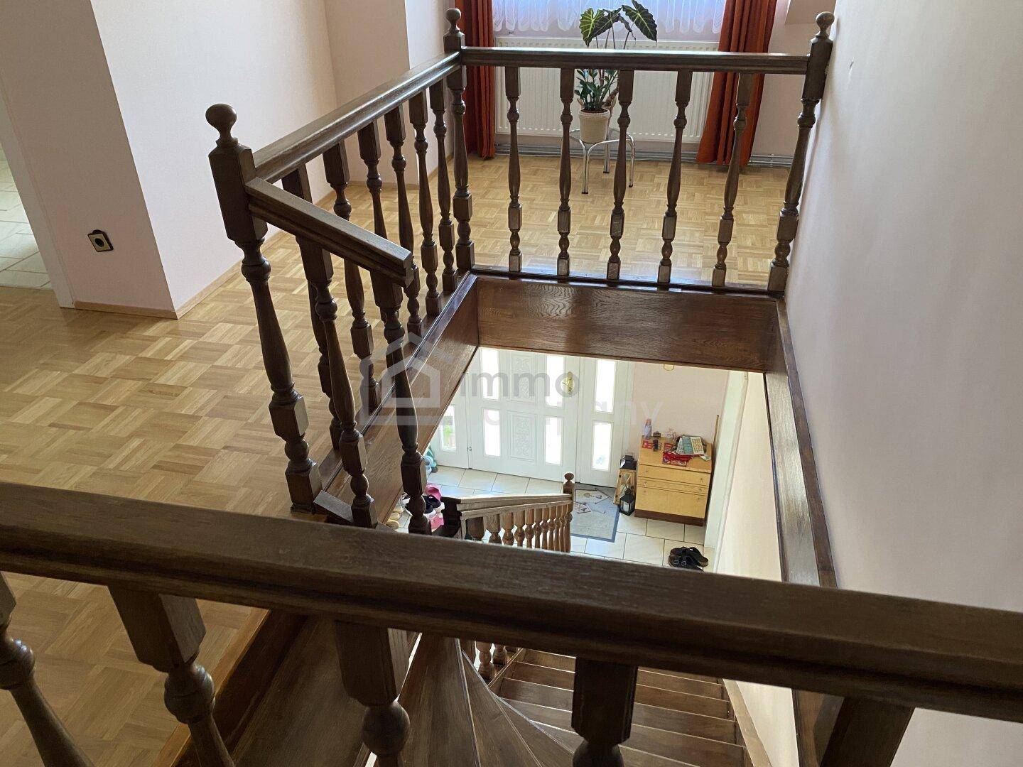 Holztreppe mit Geländer, die das Erdgeschoss mit den oberen Etagen verbindet.