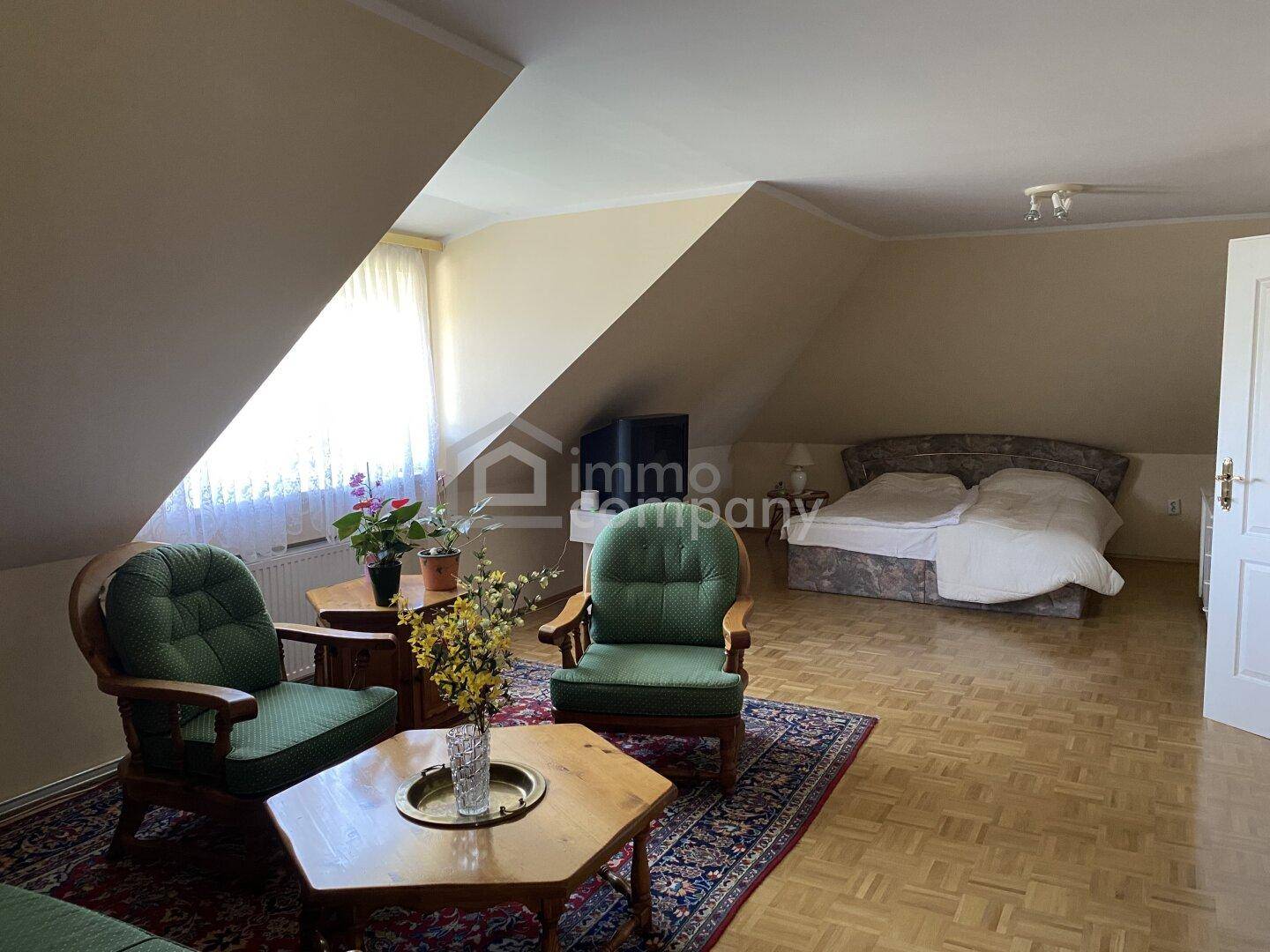 Geräumiges Schlafzimmer im Dachgeschoss mit Sitzbereich, Doppelbett und Teppich.