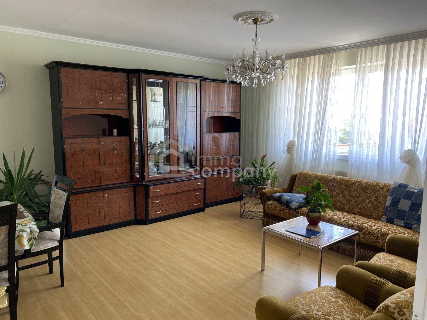 Gemütliches Wohnzimmer mit traditionellen Möbeln, Kronleuchter und hellem Parkettboden.