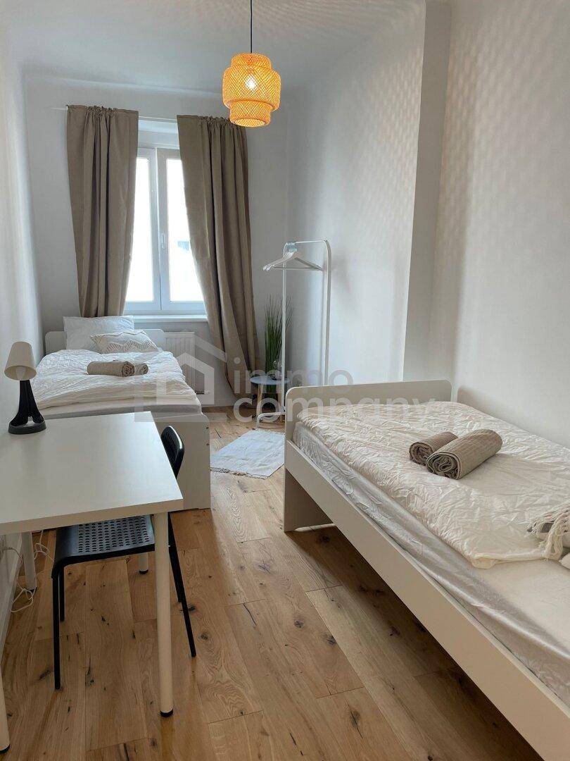 Geräumiges Schlafzimmer mit zwei Betten, Schreibtisch und Holzboden.