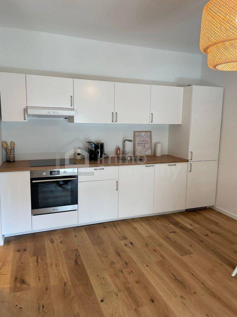 Moderne Einbauküche mit weißen Schränken, Holz-Arbeitsplatte und integrierten Geräten.