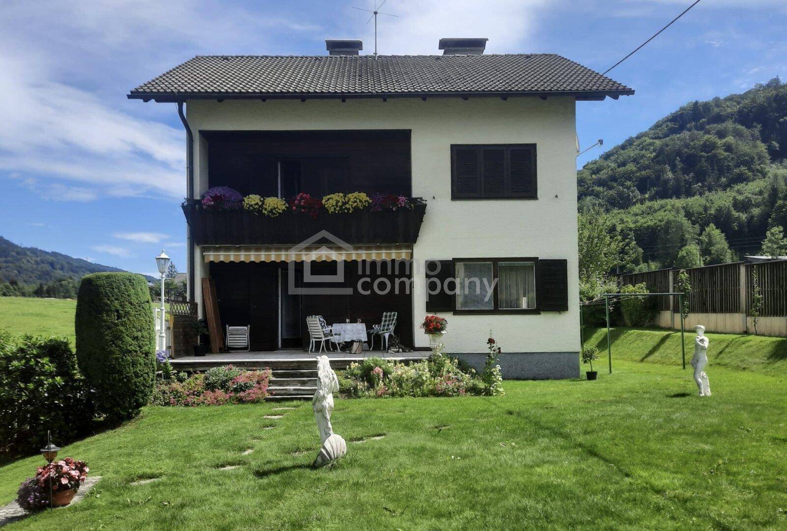 Charmantes Haus mit gepflegtem Garten, Terrasse und Bergblick in ländlicher Umgebung.