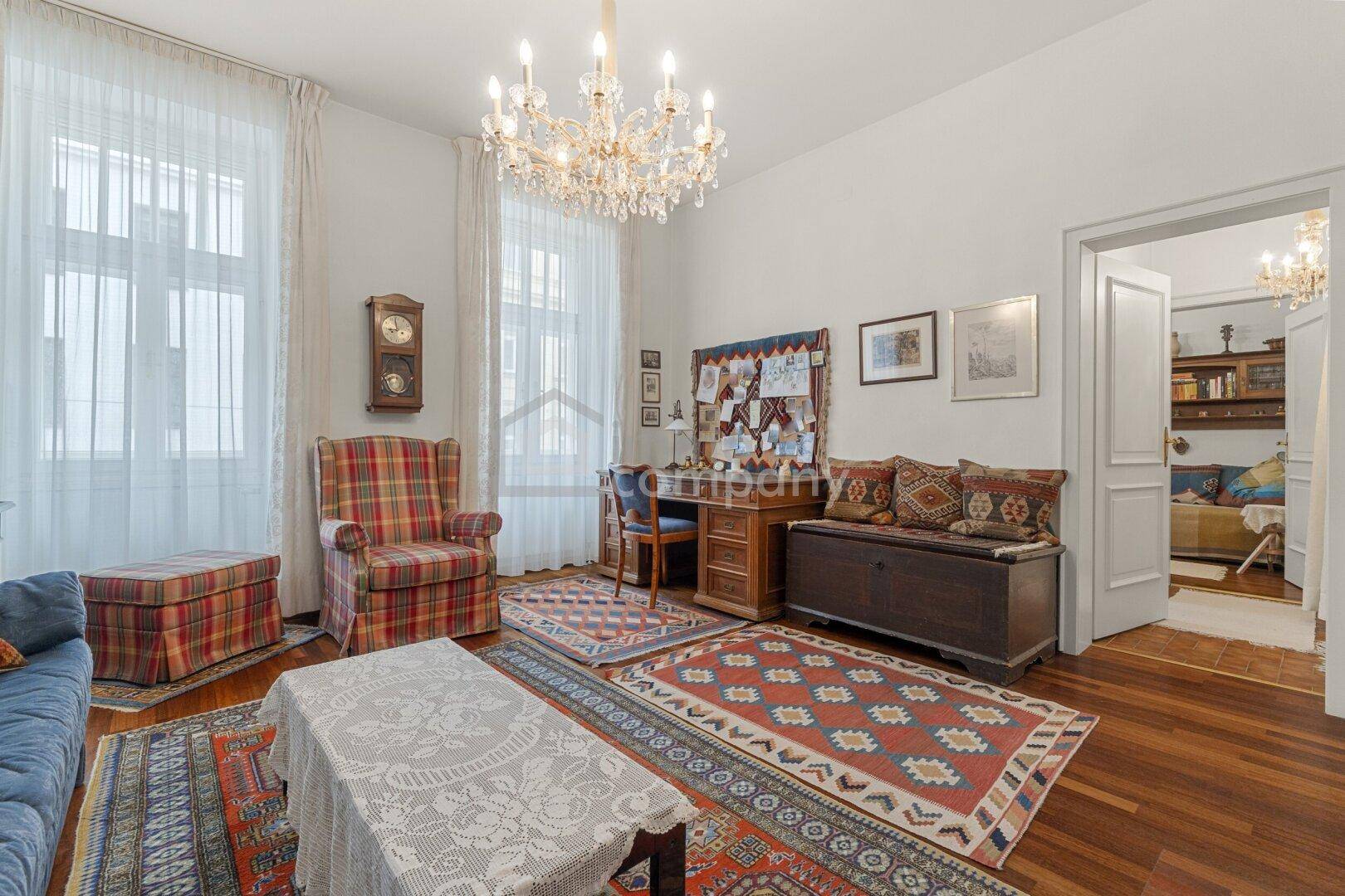 Helles Wohnzimmer mit klassischem Mobiliar, Holzboden und einem eleganten Kronleuchter.