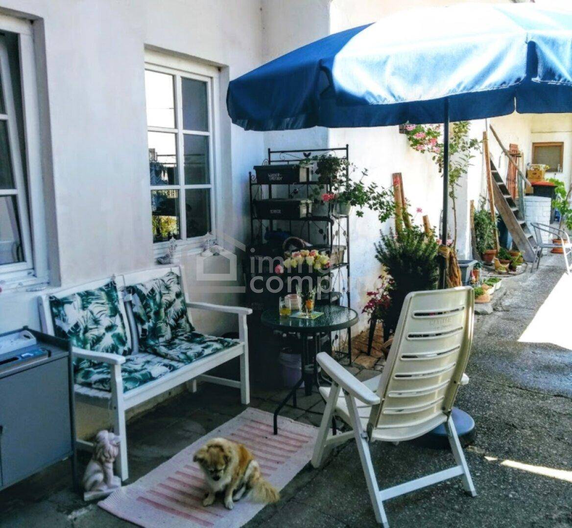 Gemütliche gepflasterte Terrasse mit Sitzbank, Sonnenschirm und Pflanzen für entspannte Stunden.