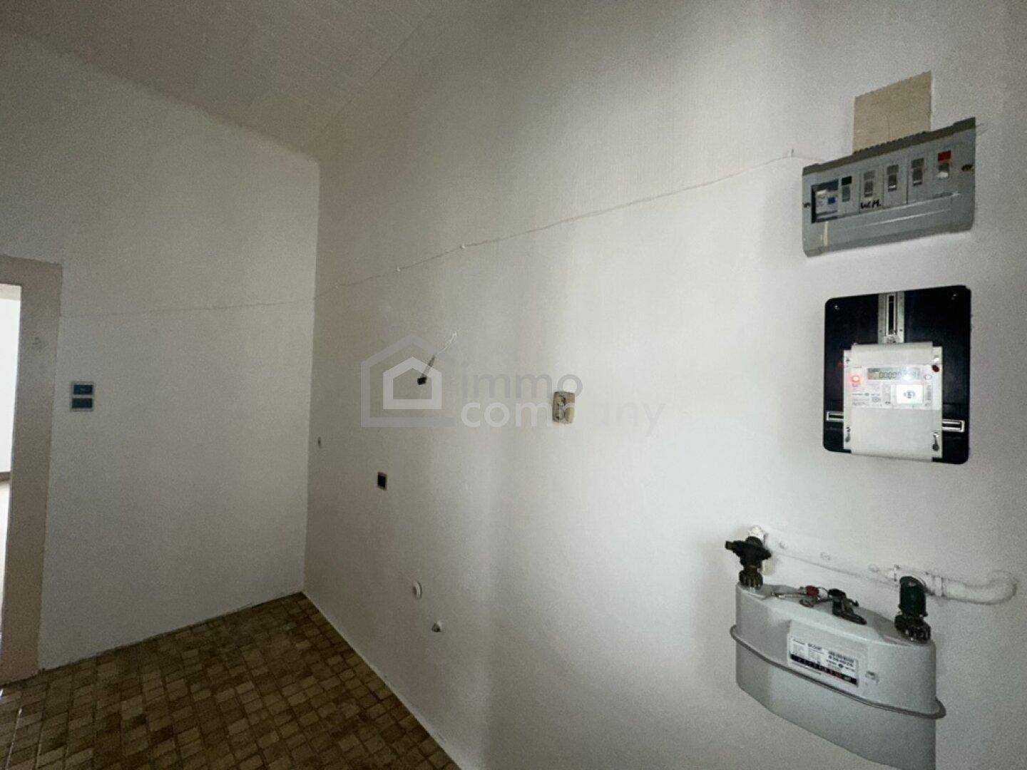 Hauswirtschaftsraum mit Gas- und Stromzählern sowie Fliesenboden, benötigt Renovierung.