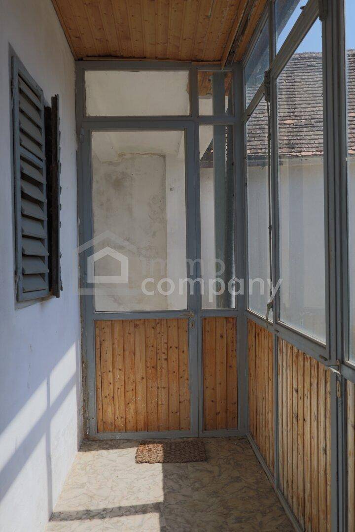 Verglaster Wintergarten oder Loggia mit Holzverkleidung und Blick nach draußen.