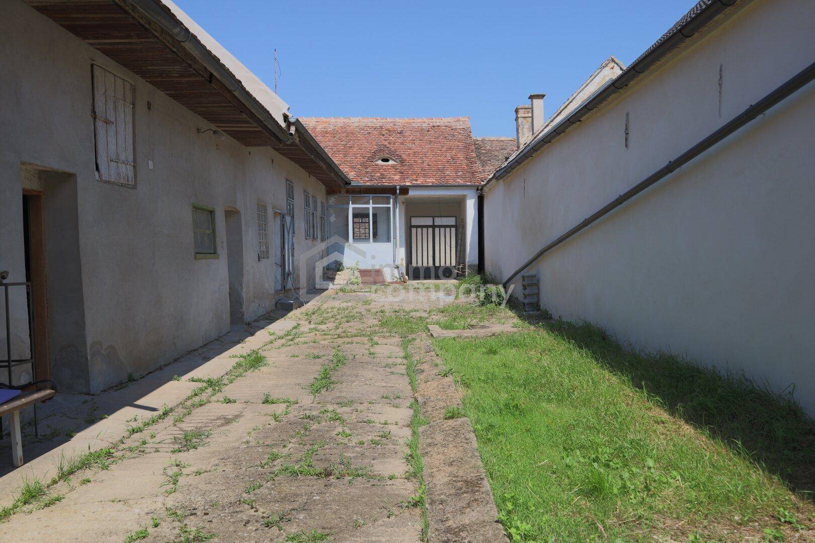 Langer gepflasterter Hof zwischen alten Gebäuden, führt zu einem weiteren Eingang.