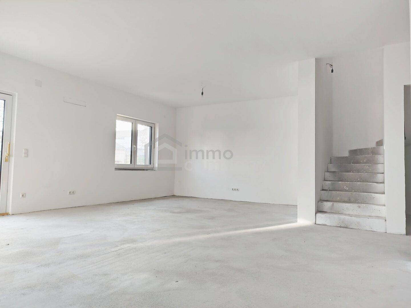 Heller, unmöblierter Innenraum mit großen Fenstern und Treppenaufgang, bereit für den Ausbau.