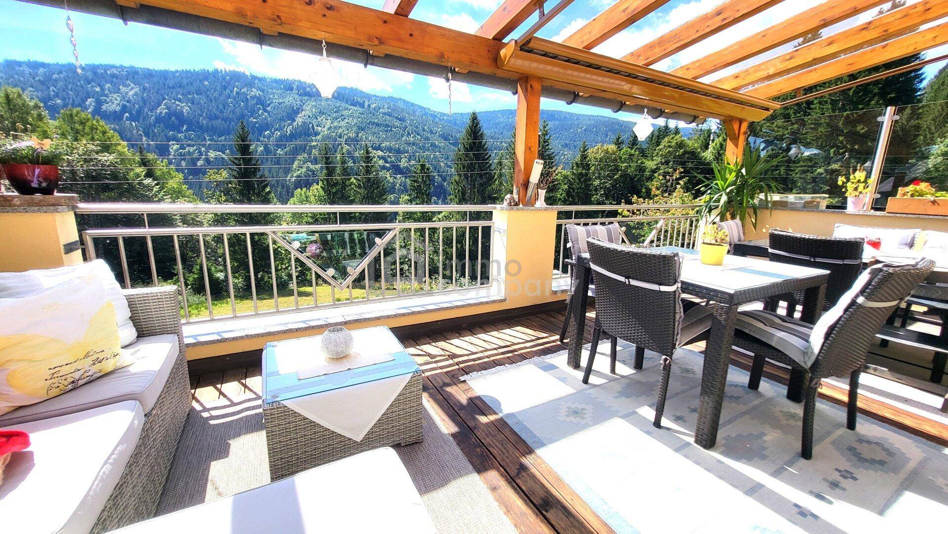 Große überdachte Terrasse mit Sitzgelegenheiten und Panoramablick auf die Berge.