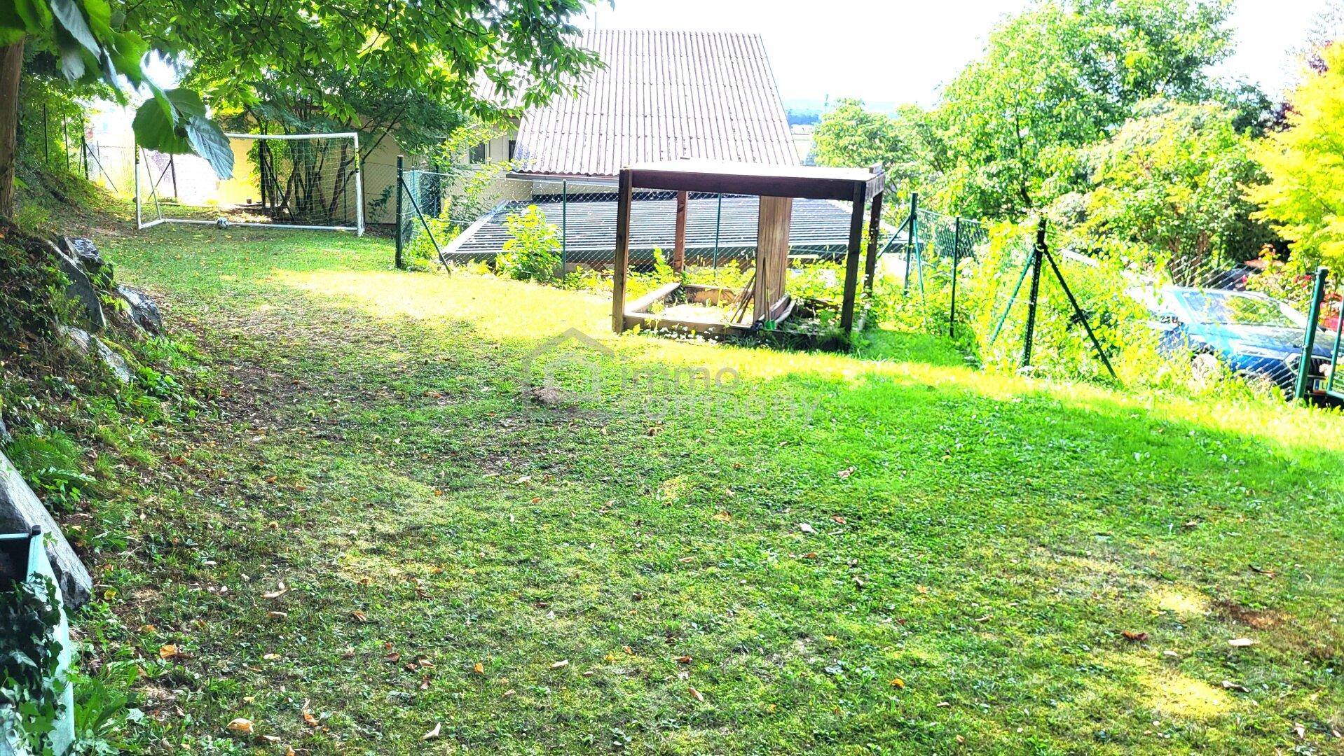 Großer Gartenbereich mit Rasenfläche, Sandkasten und Fußballtor für Kinder.
