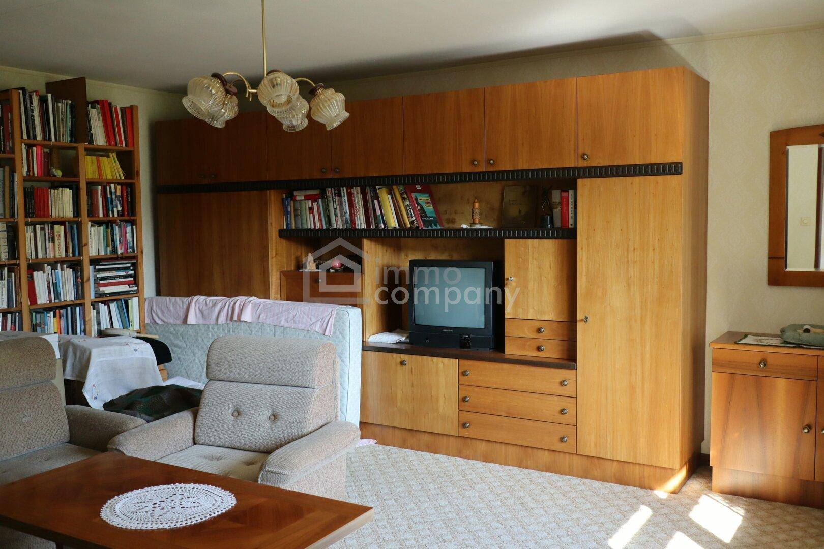 Gemütliches Wohnzimmer mit großer Holzschrankwand, Sofa und Bücherregal in klassischem Stil.