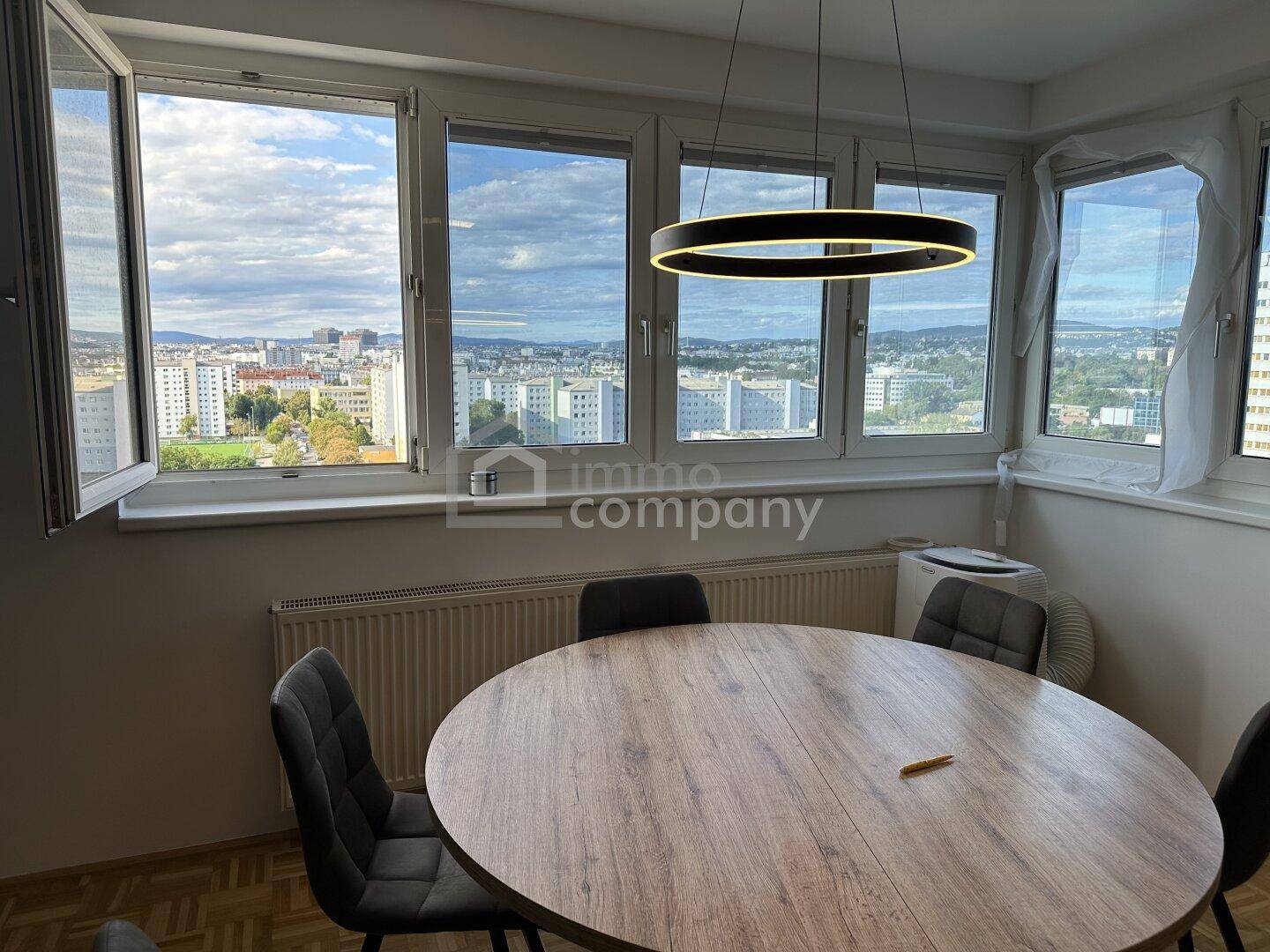 Heller Essbereich mit Panoramablick über die Stadt durch große Fenster.