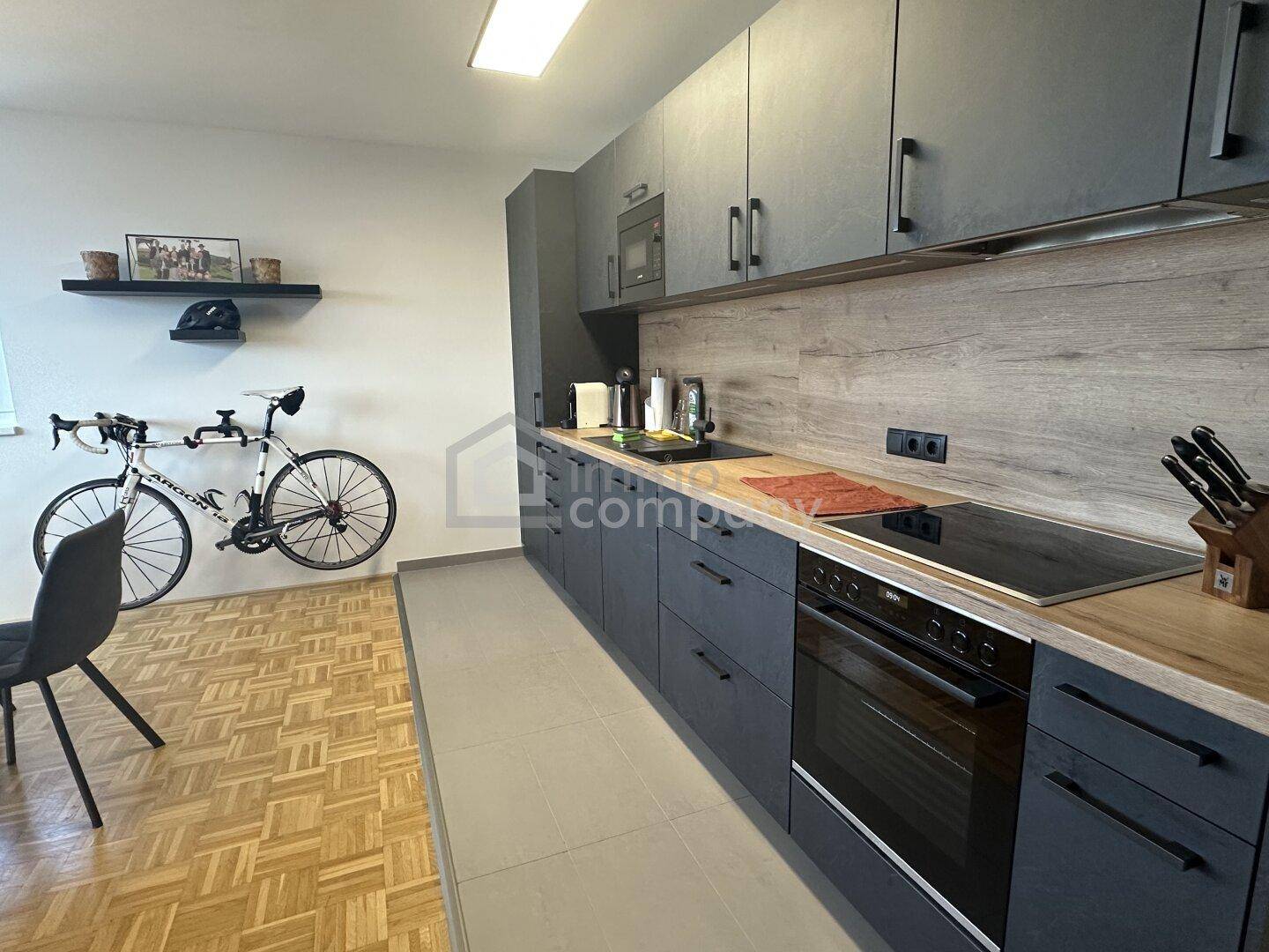 Detailansicht der modernen Einbauküche mit Induktionskochfeld, Backofen und Holzarbeitsplatte.
