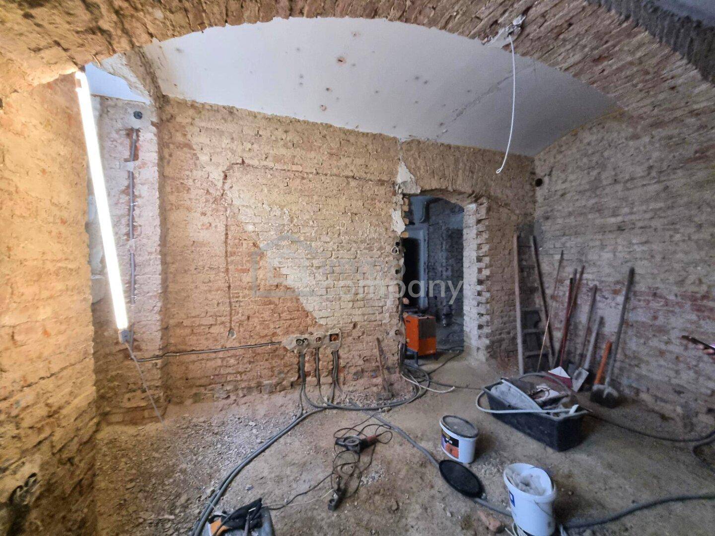 Weiterer Blick in den Rohbau mit freiliegenden Ziegelwänden und einem Durchgangsbogen.