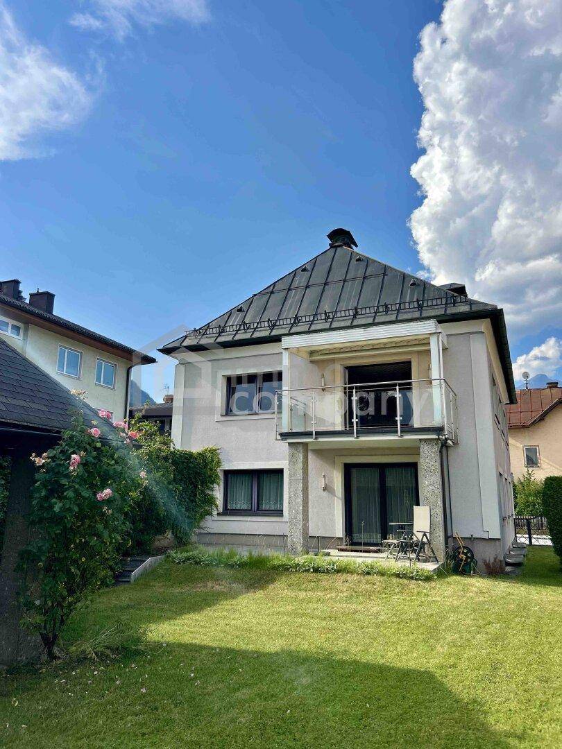 Rückseite des Hauses mit Balkon, Zugang zum Garten und gepflegter Rasenfläche.