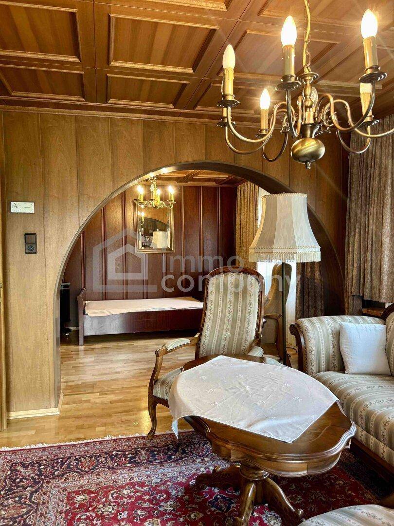 Traditionelles Wohnzimmer mit Holztäfelung, Kassettendecke und klassischem Mobiliar.