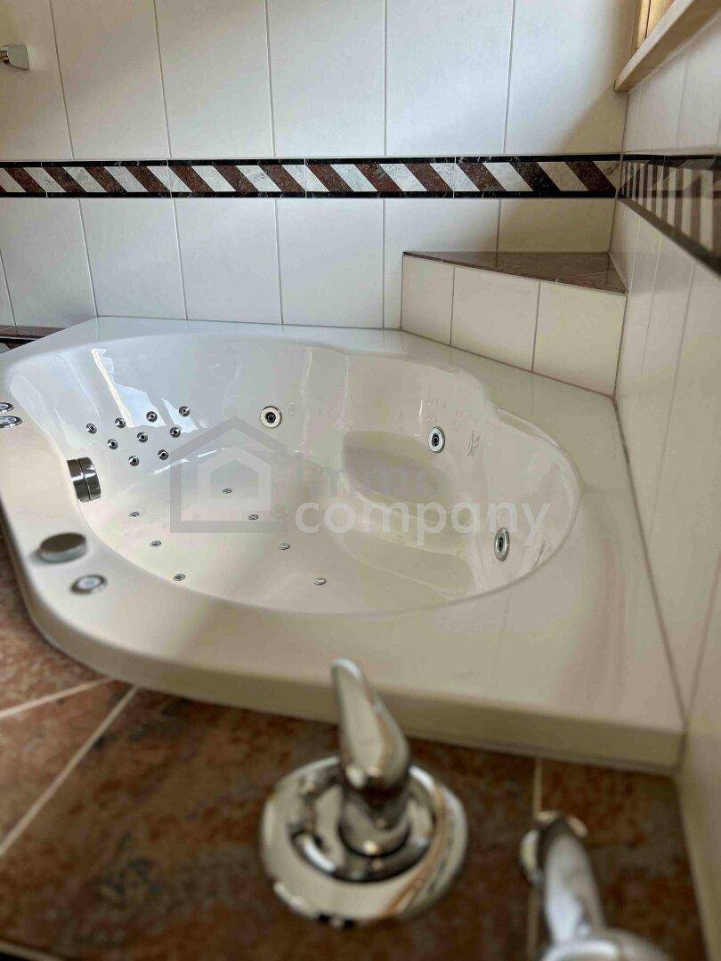 Badezimmer mit großer Eckbadewanne und Whirlpool-Funktion für Entspannung.