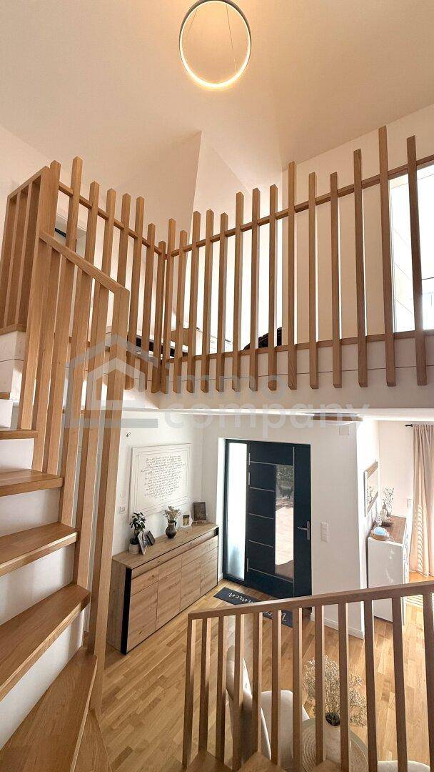 Moderner Eingangsbereich mit Holztreppe, Galerie und hellem Parkettboden, der viel natürliches Licht erhält.