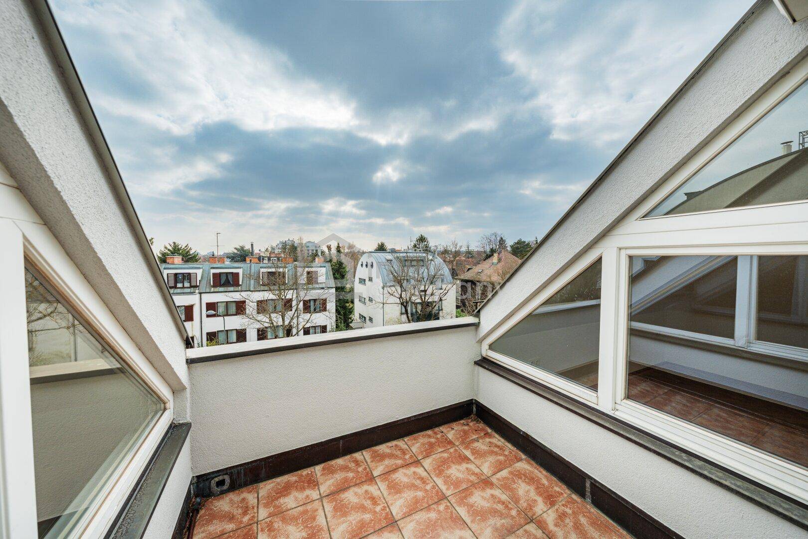 Kleine Dachterrasse mit Fliesenboden und weitem Blick über die umliegende Bebauung.