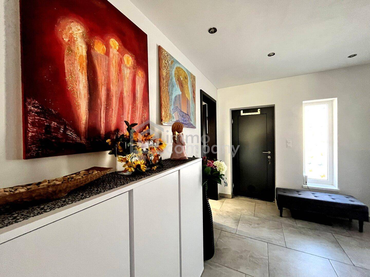 Heller Eingangsbereich mit Fliesenboden, moderner Kunst und einer praktischen Sitzbank.