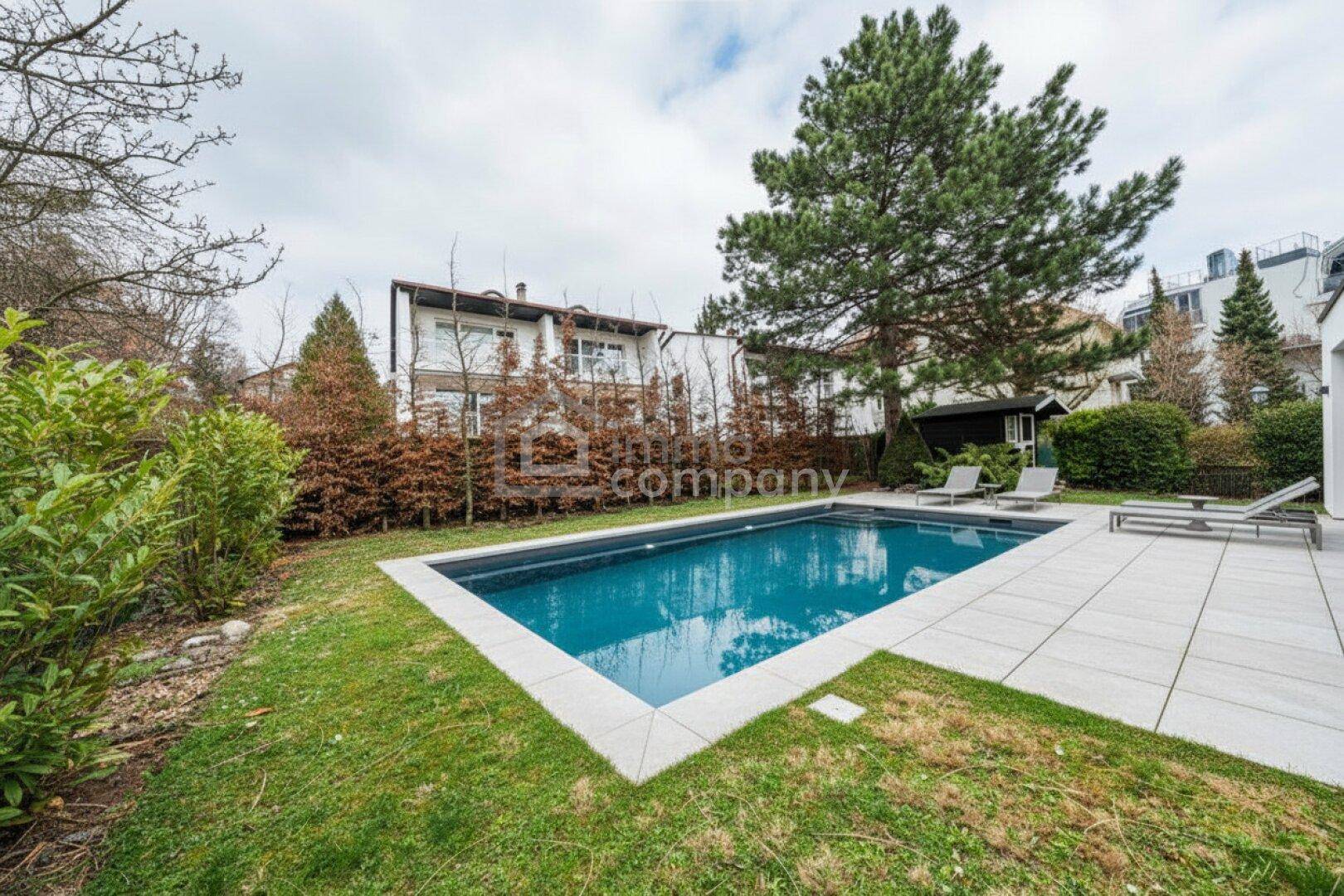 Gepflegter Gartenbereich mit rechteckigem Pool, Liegestühlen und umgebender Bepflanzung.