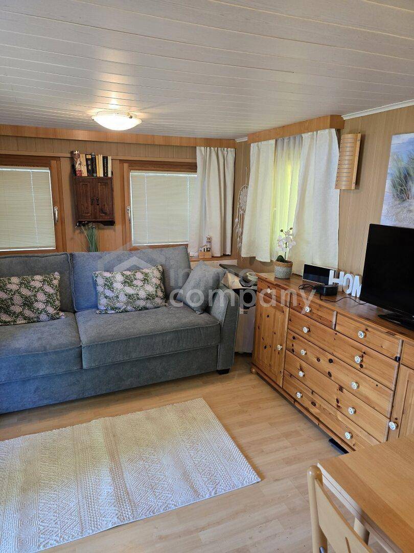 Helles und gemütliches Wohnzimmer mit Holzvertäfelung, bequemer Couch und rustikalen Möbeln.