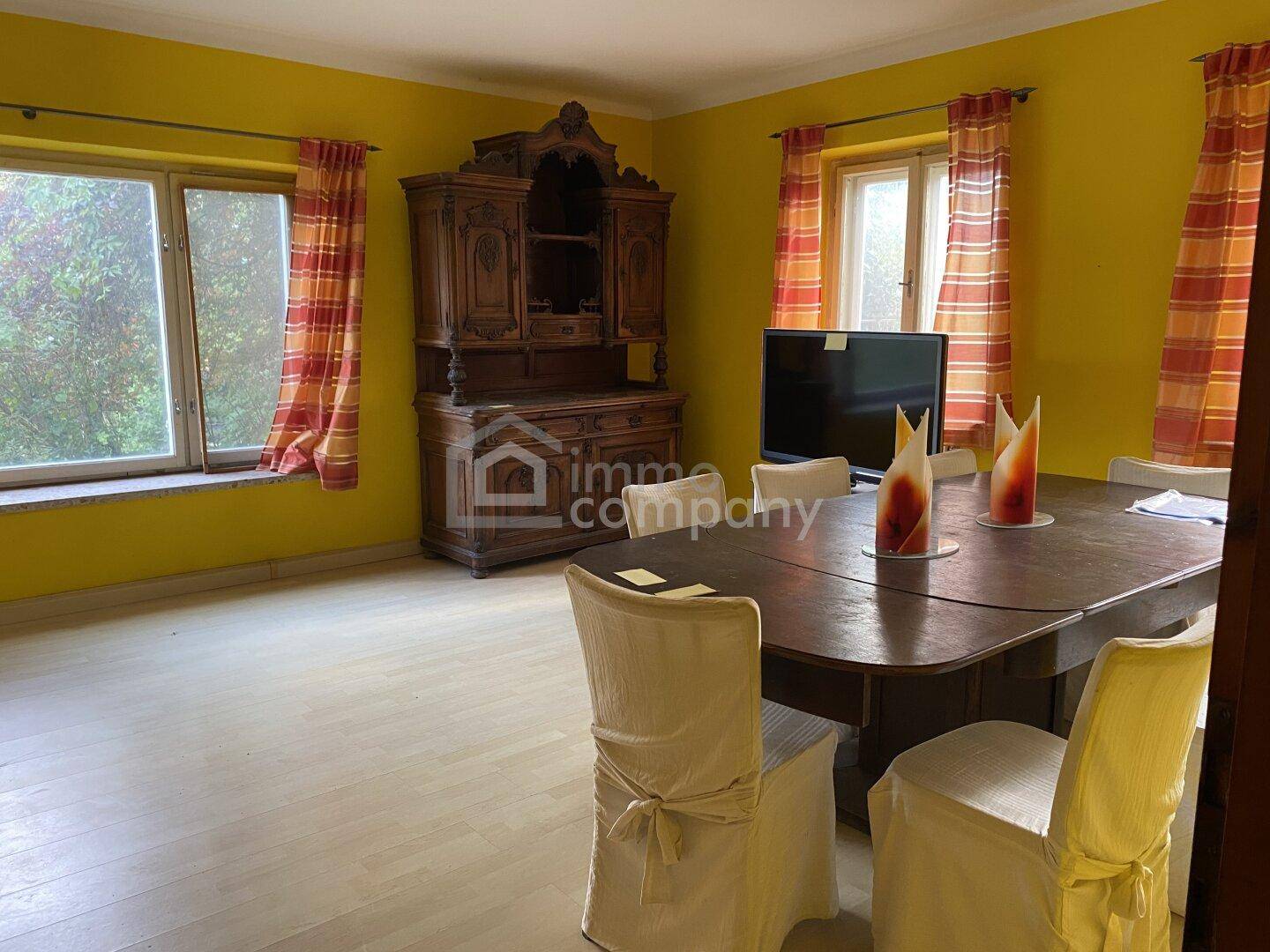 Heller Essbereich mit gelben Wänden, traditionellem Schrank und Blick ins Grüne.