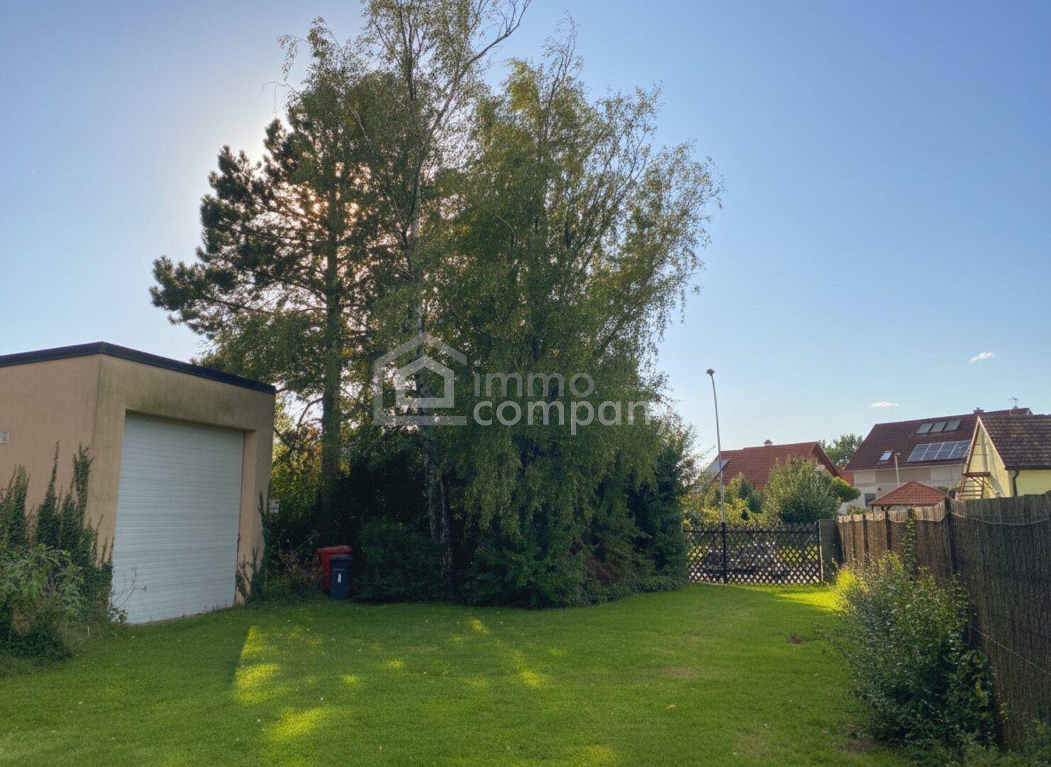 Geräumiger Gartenbereich mit Rasenfläche und einer separaten Garage im Hintergrund.